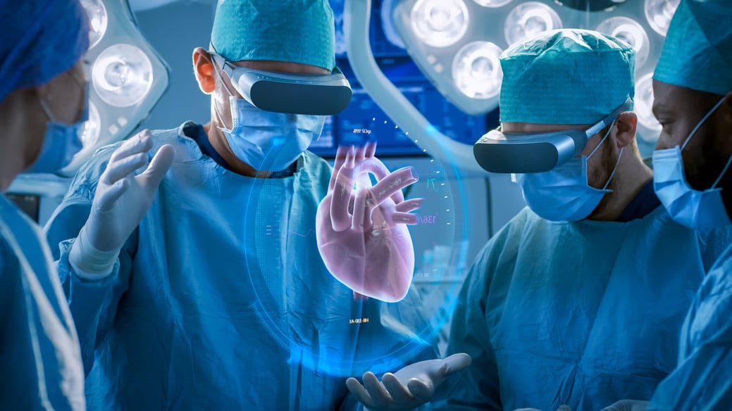 Doctors wearing virtual reality headsets performing surgery with a holographic heart model projected between them, demonstrating the use of mixed reality technology in medical procedures.