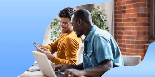 two coworkers in a casual office setting looking at an employee experience app in a mobile phone together