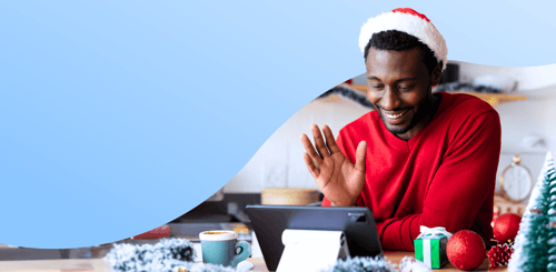 Happy employee wearing a Santa hat, using tablet for video call, surrounded by Christmas decorations